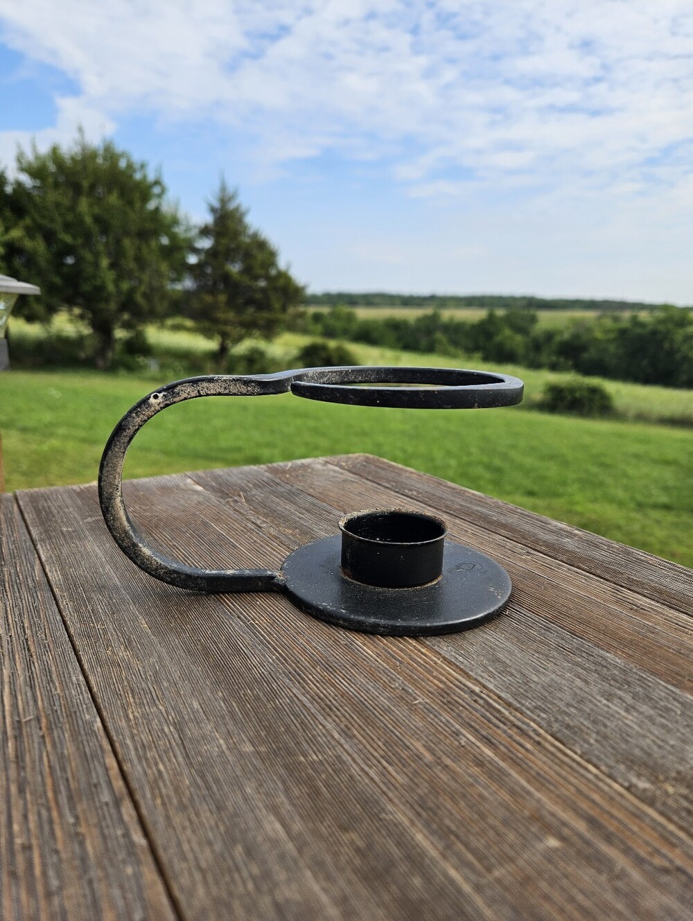 Black metal candle holder with a curved arm and circular base